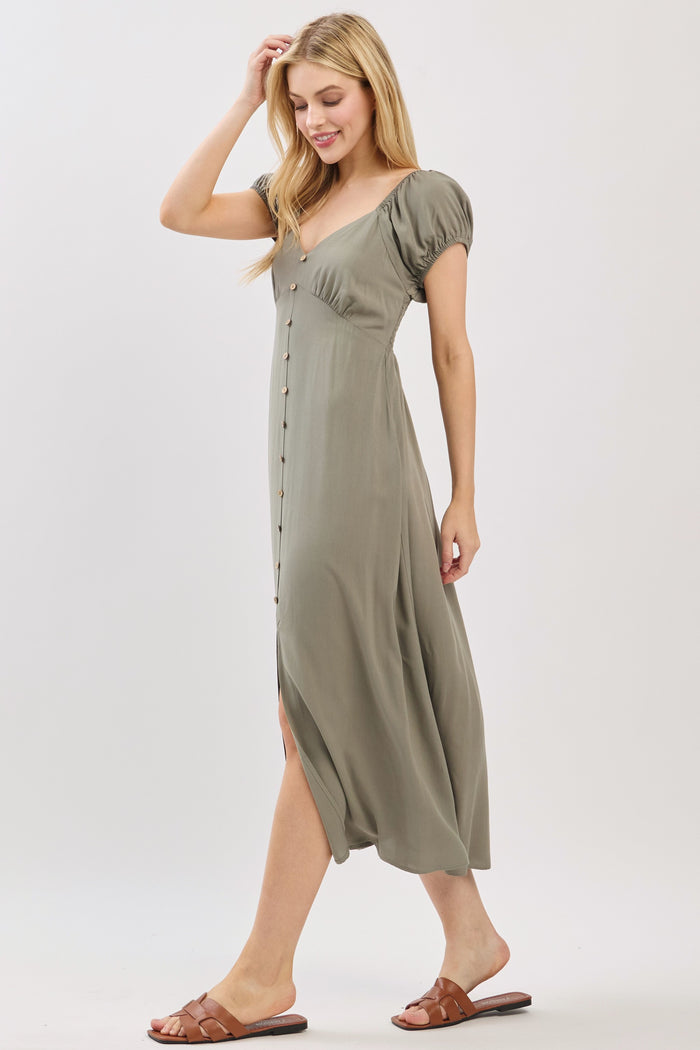 woman wearing a sage green button-up midi dress with puff sleeves and a side slit, walking in sandals