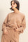woman wearing a beige oversized sweatshirt with dropped shoulders and long sleeves, styled with matching sweatpants