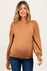 woman wearing a brown maternity sweater with puffed sleeves and a visible baby bump