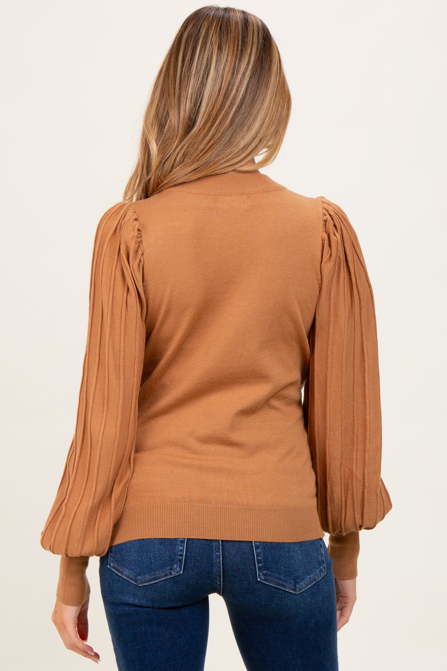 woman wearing a brown maternity sweater with puffed sleeves, view from the back