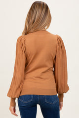 woman wearing a brown maternity sweater with puffed sleeves, view from the back