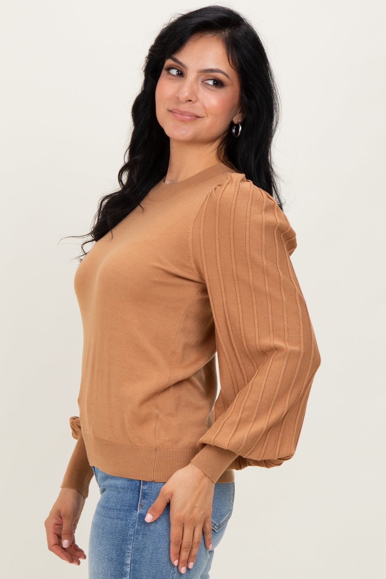 woman wearing a brown sweater with ribbed puff sleeves and a round neckline, styled with skinny jeans