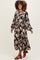 woman wearing a black floral maternity maxi dress with long sleeves and a tiered skirt, showcasing a baby bump