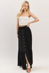 woman wearing a white cropped tank top and a black maxi skirt with buttons and a side slit