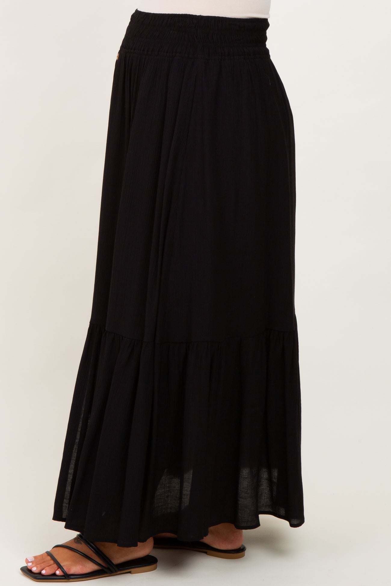 woman wearing a black maternity maxi skirt with a tiered design and elastic waistband