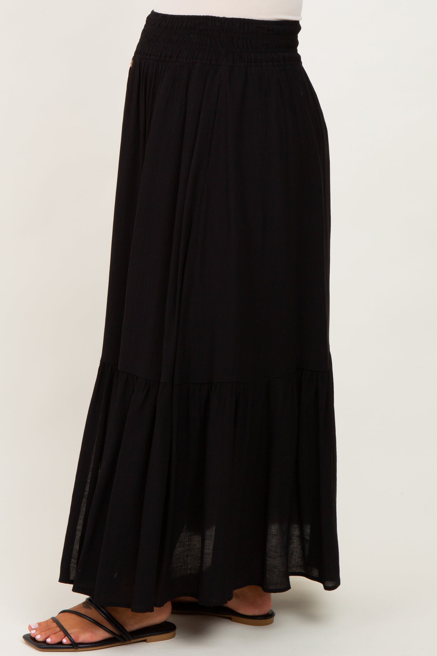 woman wearing a black maternity maxi skirt with a tiered design and elastic waistband
