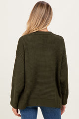 woman wearing a dark green oversized maternity sweater viewed from the back, with a cozy knit texture and relaxed fit