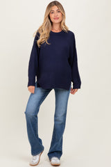 woman wearing a navy blue cozy maternity sweater with a loose fit and light blue flared jeans