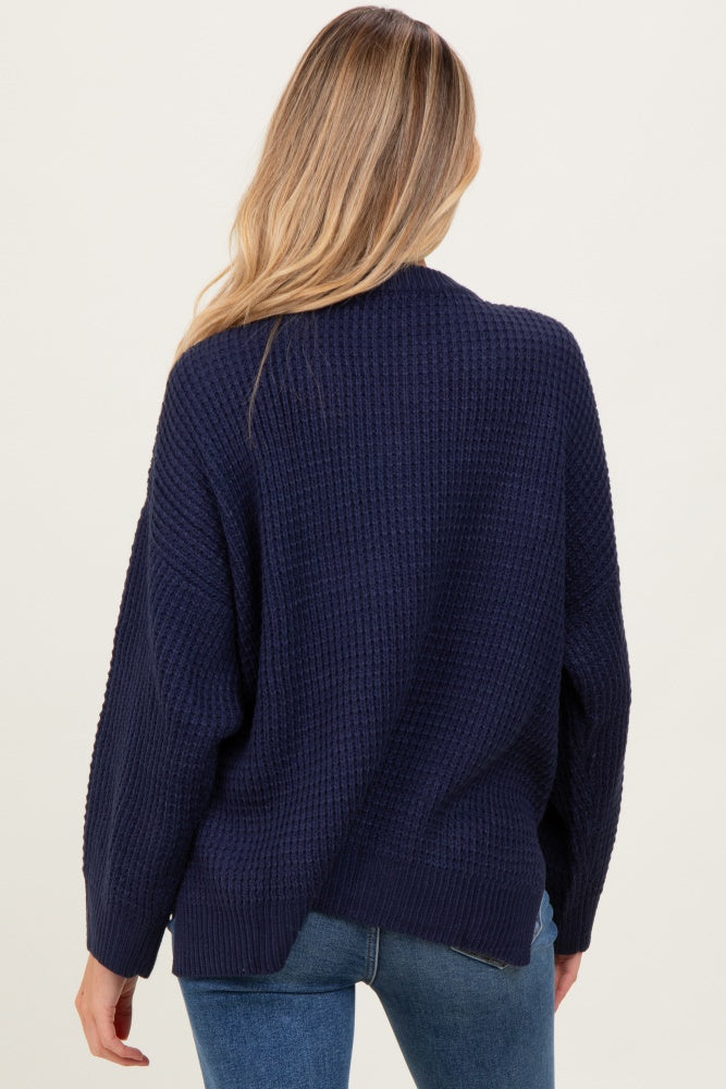 woman wearing a navy blue oversized knitted maternity sweater, showing the back view with a relaxed fit