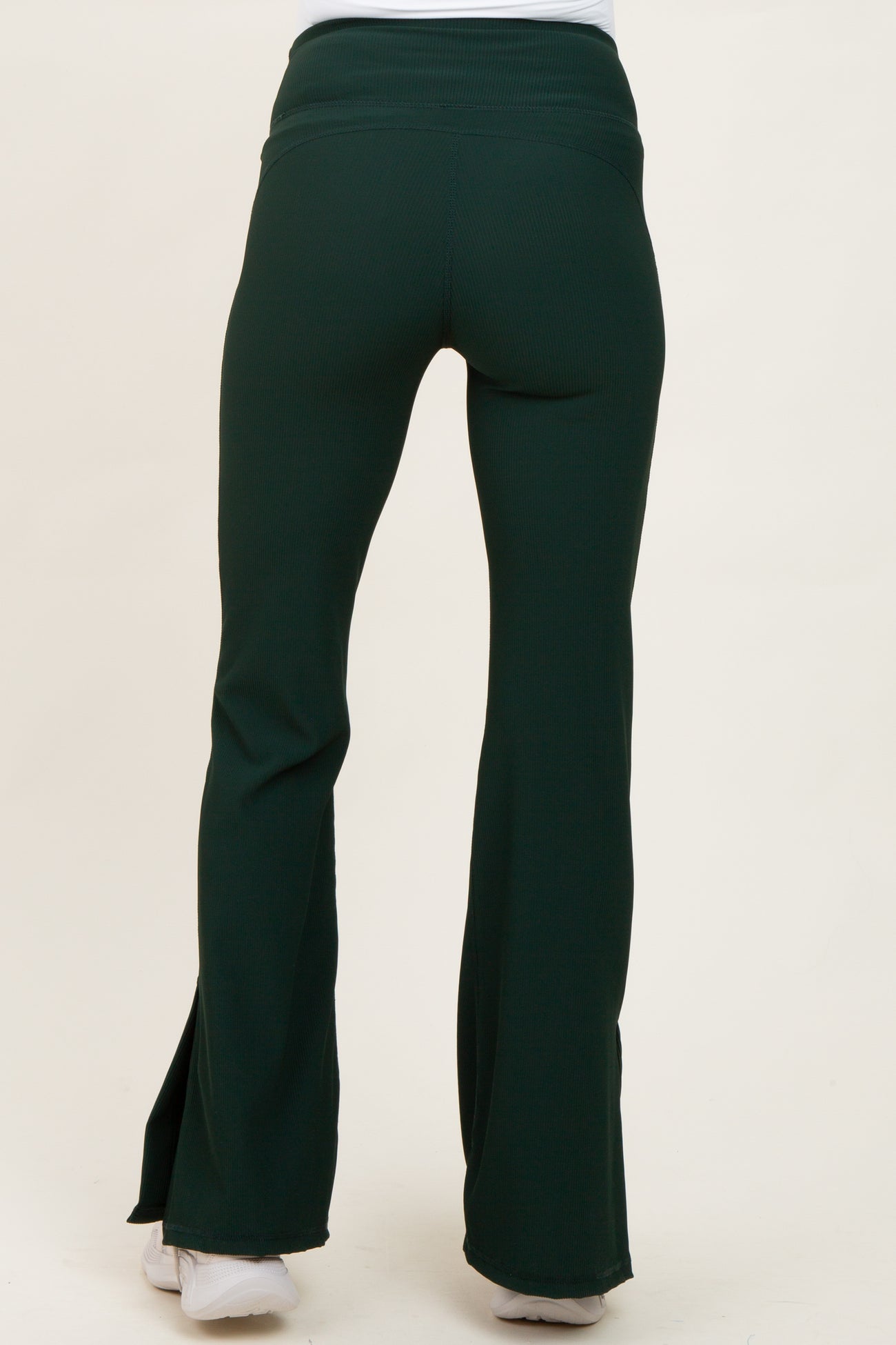 woman wearing green maternity flared pants with a high waistband and a fitted style, shown from the back