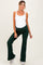 woman wearing a white maternity bodysuit and green flared maternity pants, with a visible baby bump