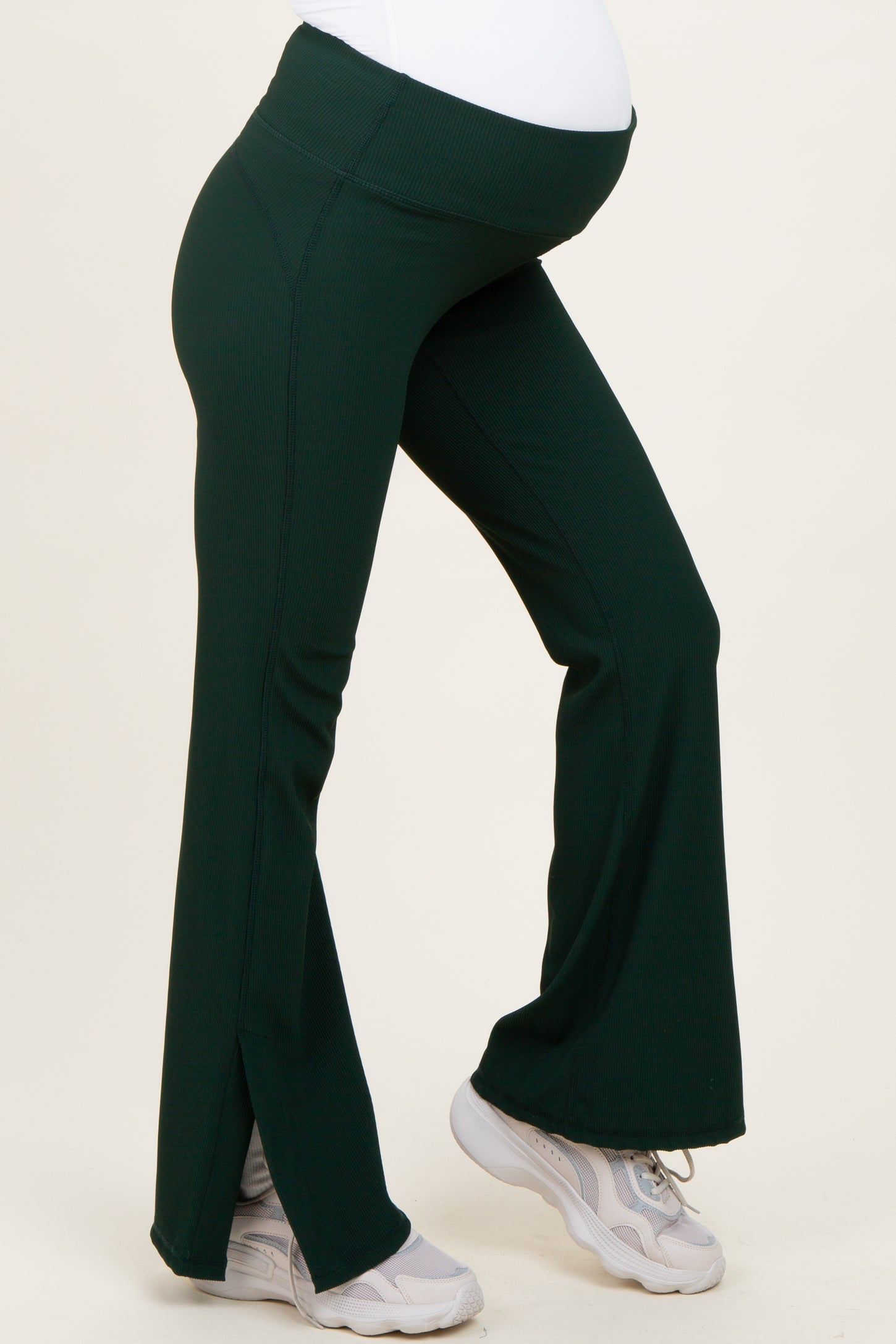 woman wearing dark green flared maternity pants with side slits and a stretchy belly panel