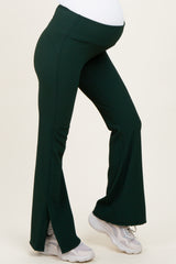 woman wearing dark green flared maternity pants with side slits and a stretchy belly panel