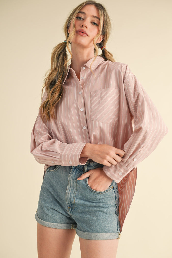 woman wearing a light pink striped button-up shirt with a pocket and high-waisted denim shorts