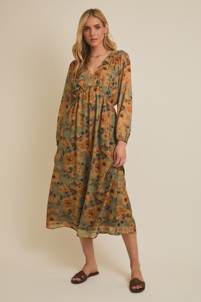 woman wearing a floral green and orange maxi dress with long sleeves and a v-neckline