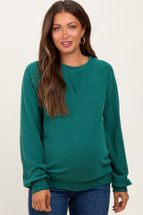 woman wearing a green ribbed maternity sweater with a relaxed fit and long sleeves, showing her baby bump