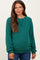 woman wearing a green ribbed maternity sweater with a relaxed fit and long sleeves, showing her baby bump