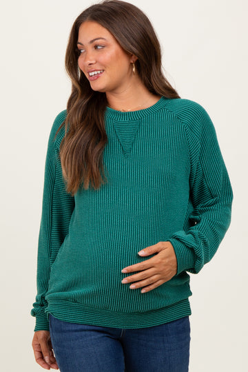 woman wearing a green ribbed maternity sweatshirt and showing her baby bump while smiling