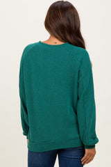 woman wearing a dark green ribbed maternity sweater seen from the back, with a relaxed fit and long sleeves