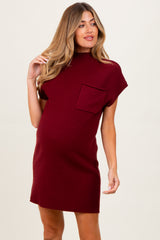 woman wearing a burgundy ribbed maternity dress with short sleeves and a front pocket, showing her baby bump