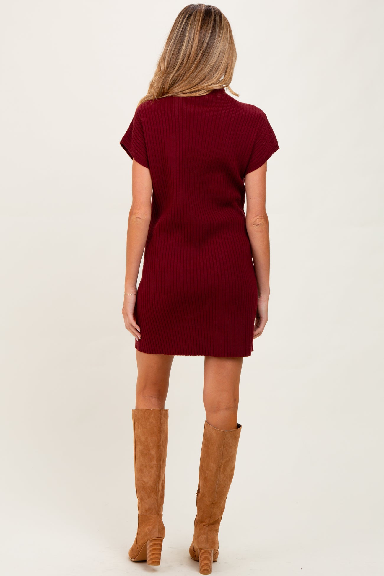 woman wearing a maroon ribbed maternity dress paired with tan knee-high boots, view from the back