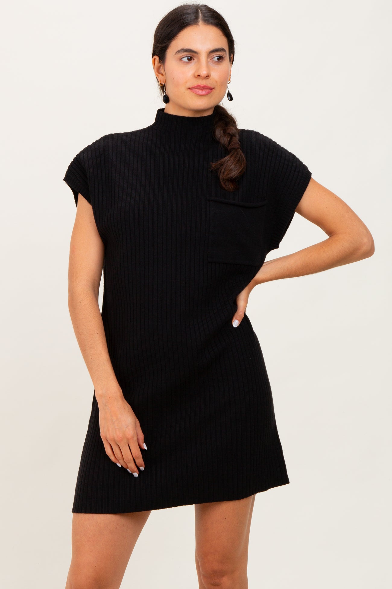 woman wearing a black ribbed short sleeve turtleneck dress with a front pocket