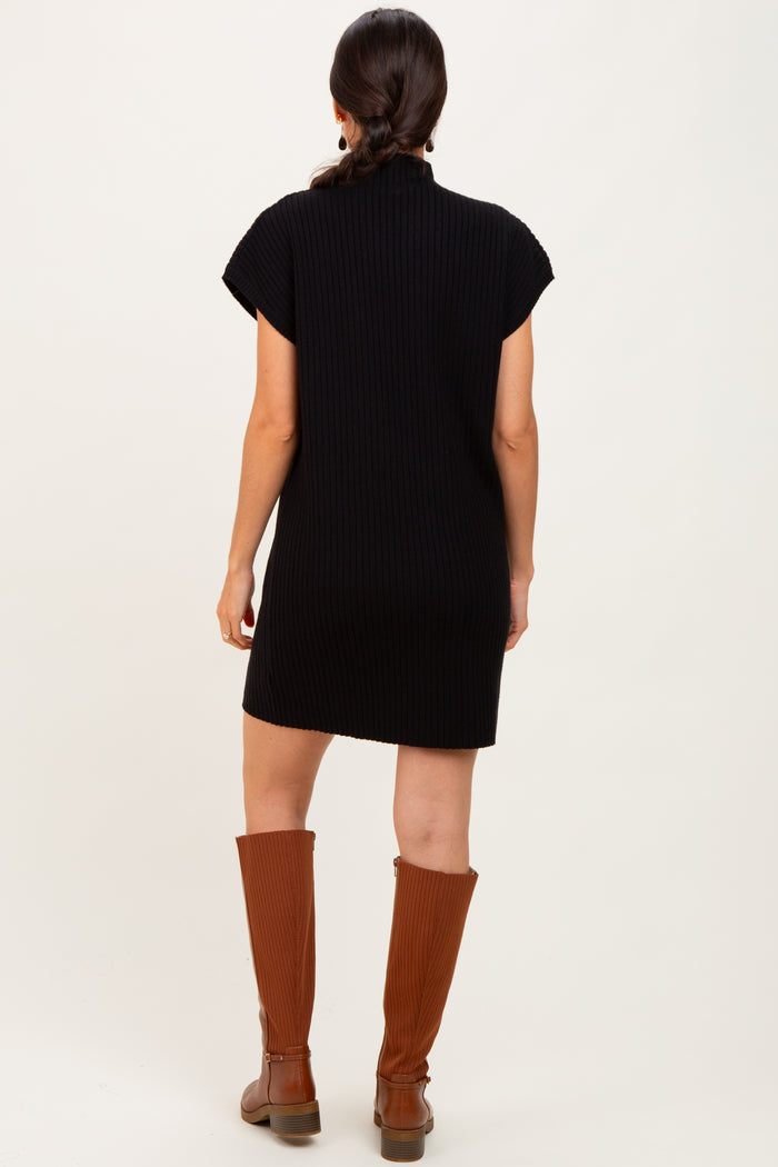 woman wearing a black ribbed short-sleeve dress and brown knee-high boots, seen from the back