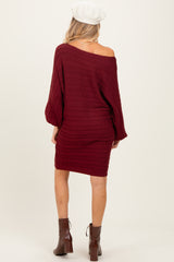 woman wearing a burgundy off-the-shoulder cable knit maternity sweater dress, view from the back