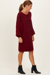woman wearing a burgundy cable knit sweater dress with balloon sleeves and ankle boots