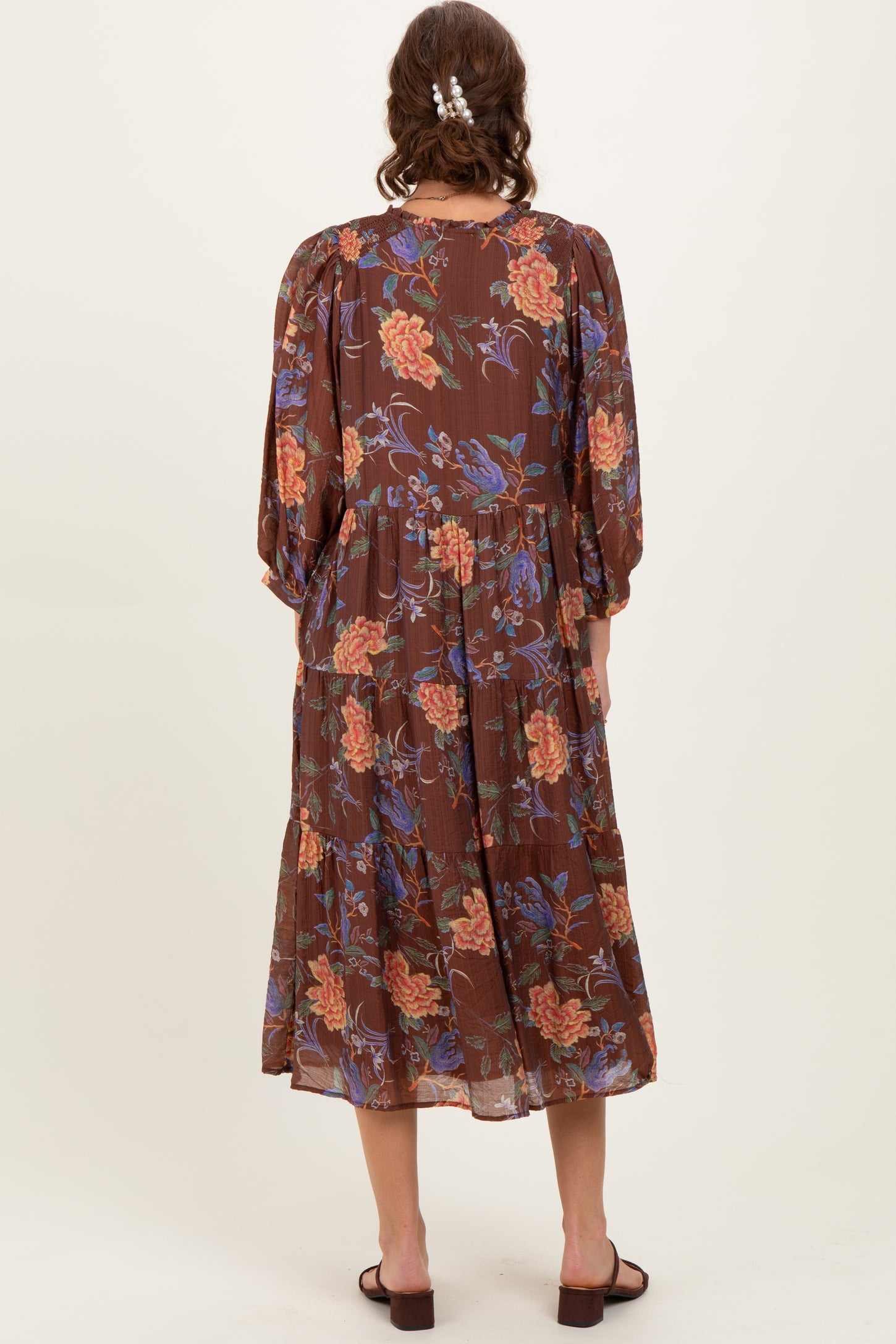 woman wearing a brown floral maxi dress with balloon sleeves, shown from the back