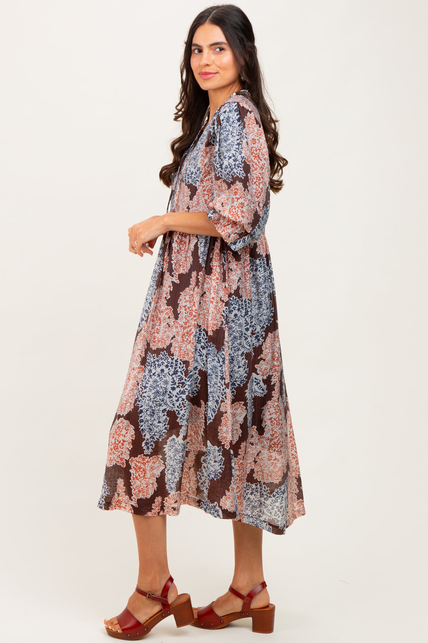 woman wearing a brown and multi-colored floral midi dress with a loose fit and short sleeves