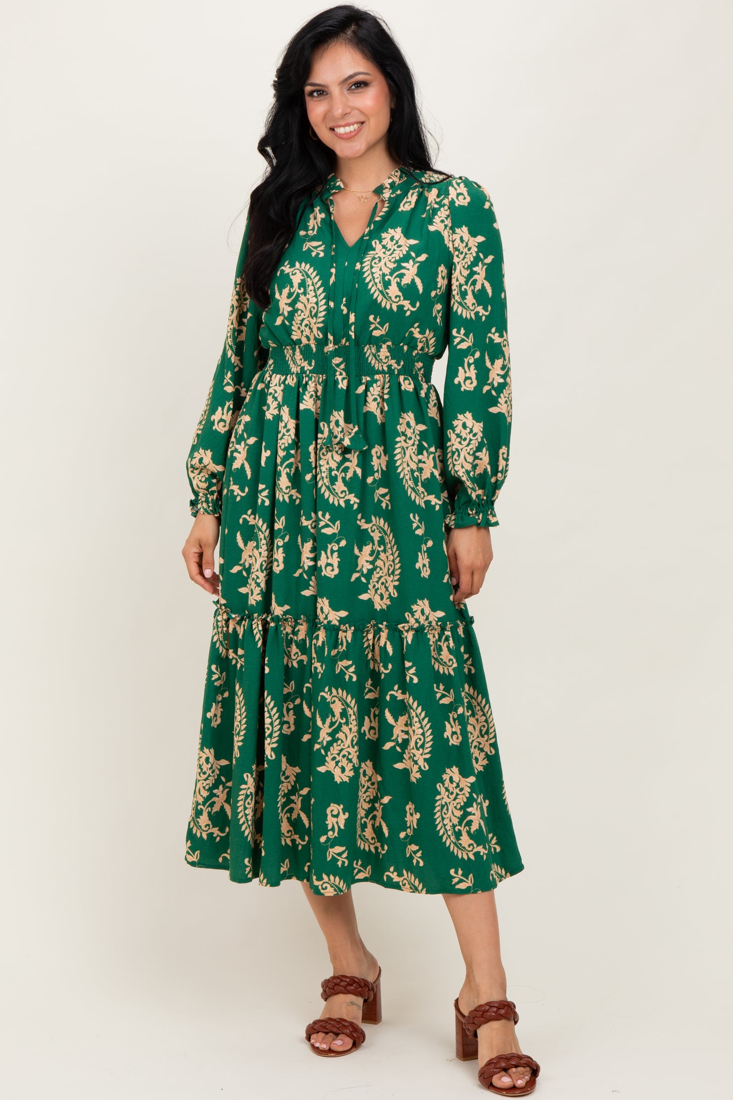 woman wearing a green floral printed maxi dress with long sleeves and a tiered skirt