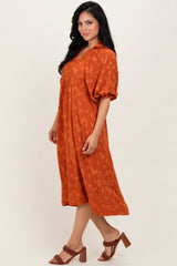 woman wearing an orange floral midi dress with puff sleeves and a buttoned neckline, paired with heeled sandals