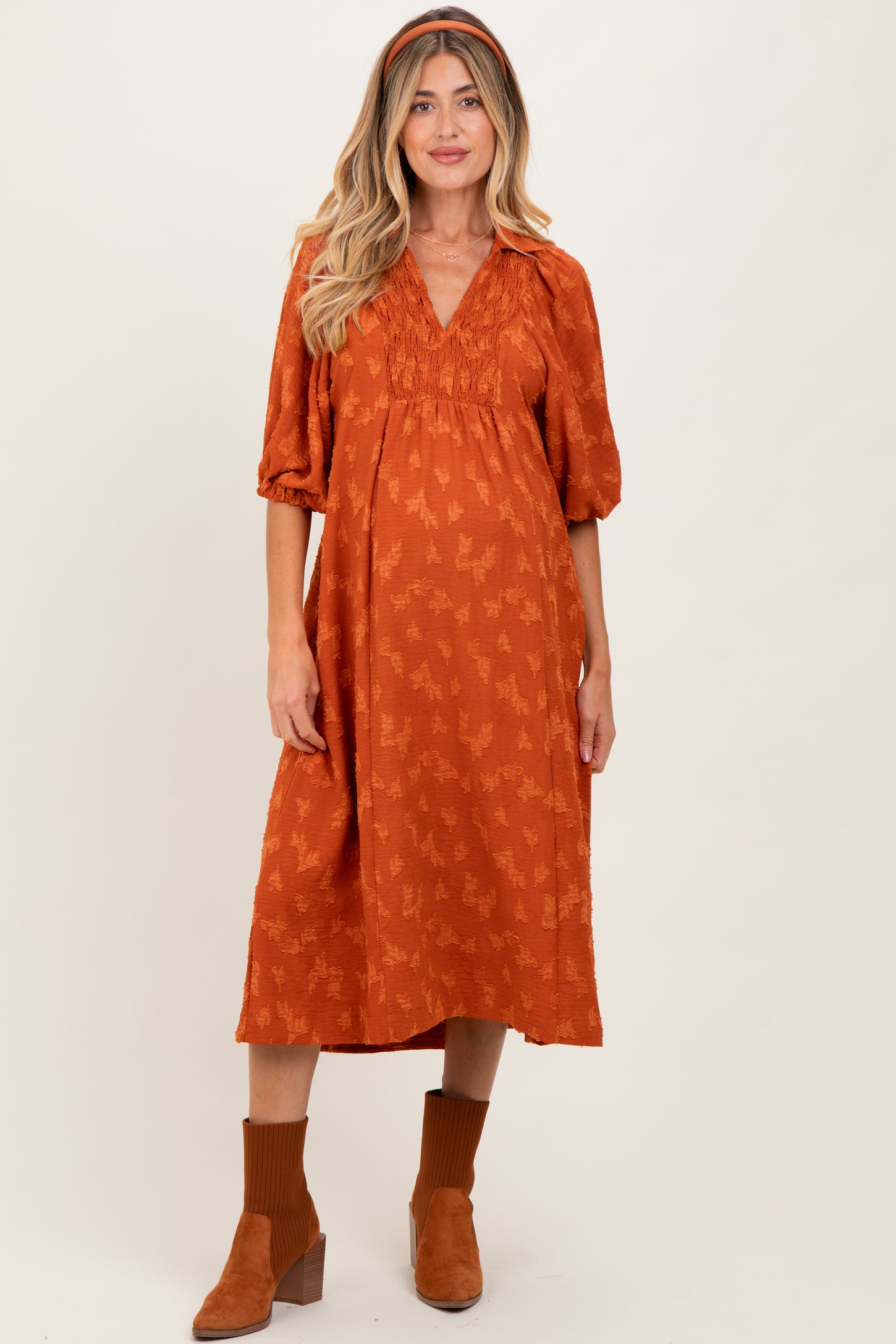 woman wearing an orange floral print maternity dress with puff sleeves and a baby bump visible