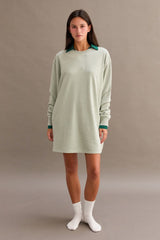 woman wearing a green oversized long sleeve dress with a dark green collar and white socks