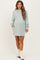 woman wearing a light green maternity sweatshirt dress with long sleeves and side pockets, showcasing her baby bump