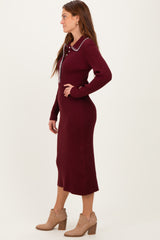 woman wearing a burgundy knitted midi dress with a collar and button detail paired with tan ankle boots