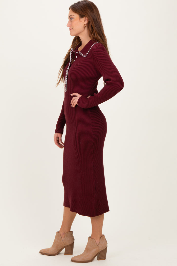 woman wearing a burgundy knitted midi dress with a collar and button detail paired with tan ankle boots