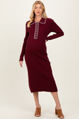 woman wearing a burgundy ribbed maternity dress with a collar and button detail, showcasing her baby bump