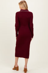 woman wearing a burgundy ribbed long sleeve maternity dress with a fitted silhouette and a mid-calf length