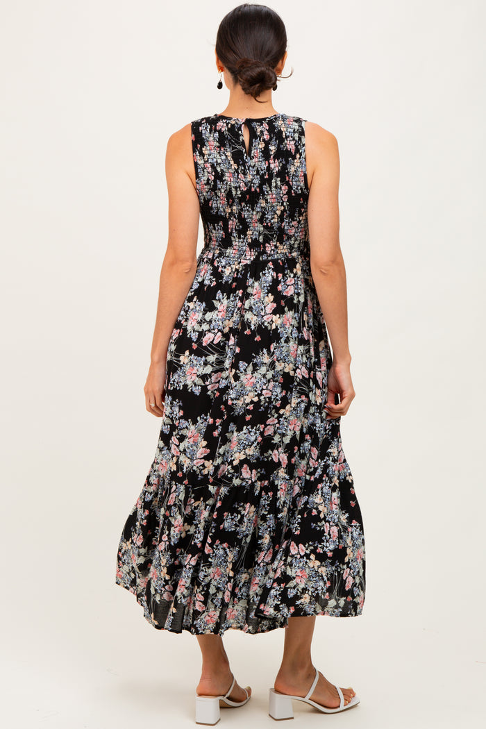 woman wearing a black floral maxi dress with a smocked waist and a flowy skirt, showing the back view
