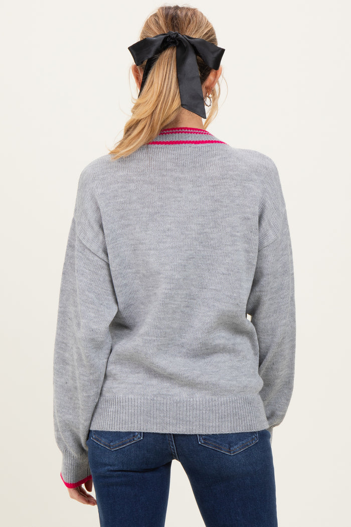 woman wearing a gray maternity sweater with pink detailing, styled with her hair in a ponytail and a black bow