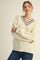 woman wearing a cream v-neck sweater with navy stripes and relaxed fit, paired with blue jeans