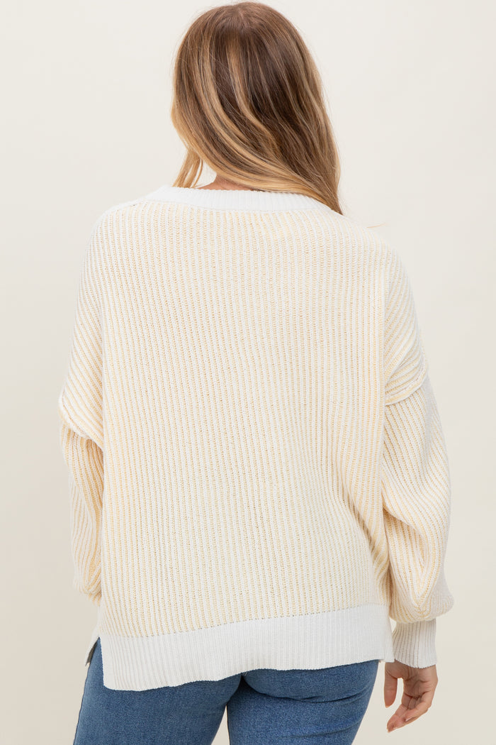women wearing a cream and soft yellow striped oversized sweater with a wide neckline and balloon sleeves