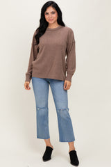 woman wearing a brown ribbed long sleeve sweater and light blue cropped jeans with a frayed hem