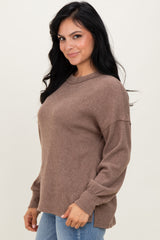 woman wearing a cozy brown ribbed sweater with long sleeves and a relaxed fit