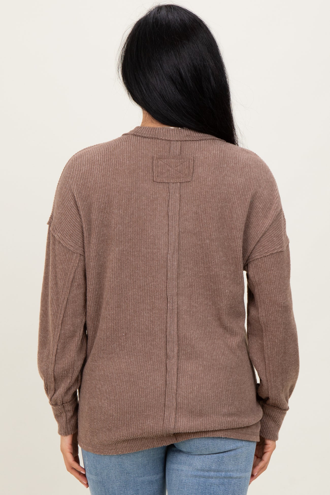 woman wearing a brown ribbed long sleeve sweater, featuring a relaxed fit and dropped shoulders, viewed from the back