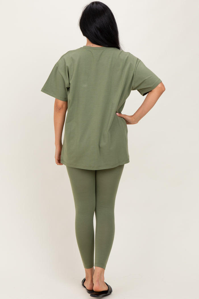 woman wearing an olive green oversized t-shirt and matching leggings, standing with her back to the camera