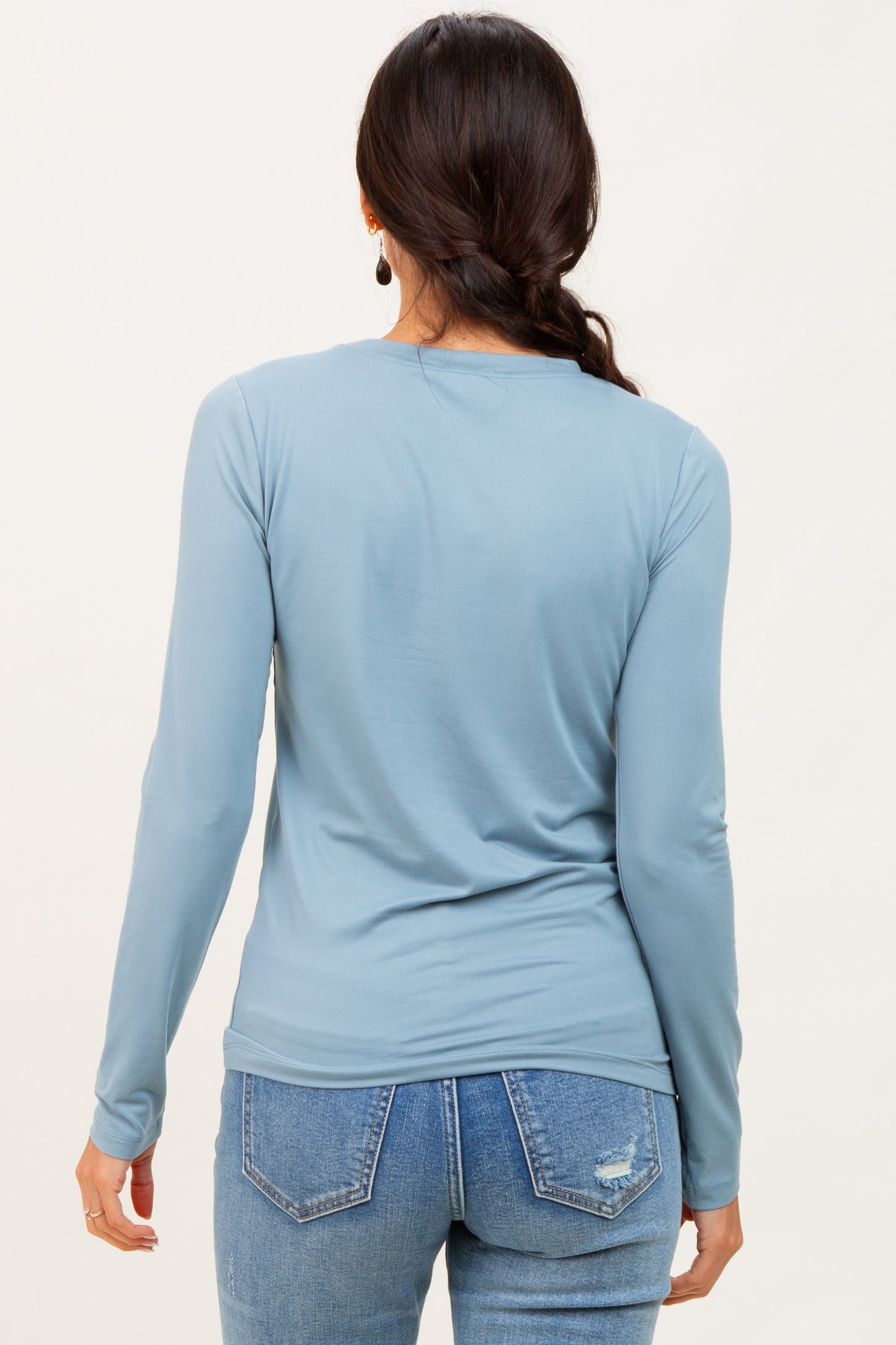 woman wearing a light blue long sleeve top paired with distressed jeans, viewed from the back