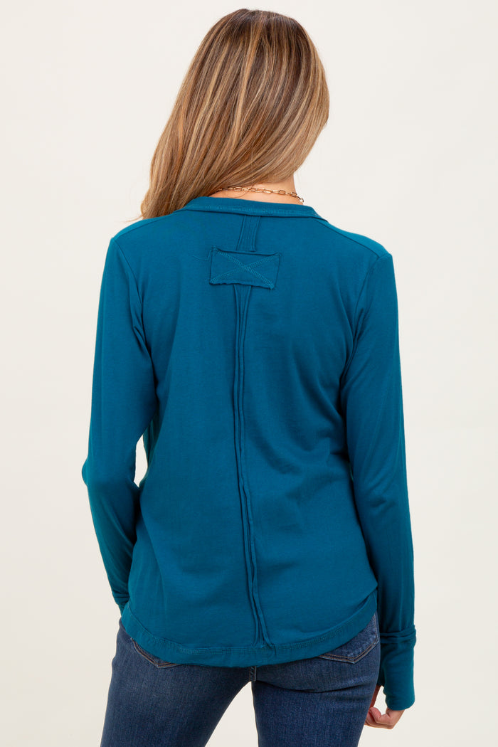 woman wearing a teal long sleeve maternity top with a stylish back detail and pairing it with jeans.